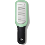 OXO Good Grips Etched Ginger & Garlic Grater with stainless steel etched teeth, soft grip handle, and snap‑on scraper cover shown in a modern kitchen setting.
