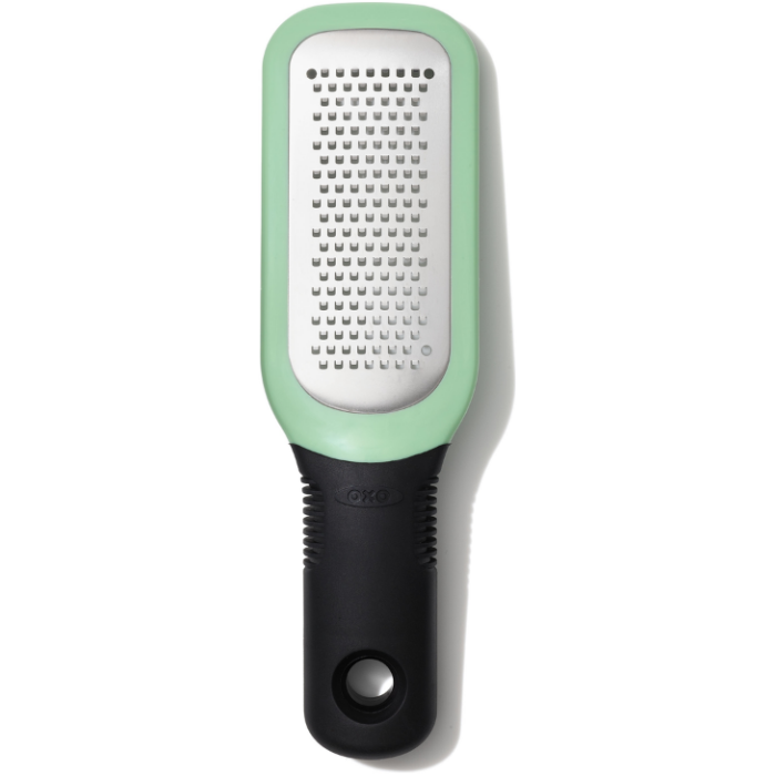 OXO Good Grips Etched Ginger & Garlic Grater with stainless steel etched teeth, soft grip handle, and snap‑on scraper cover shown in a modern kitchen setting.